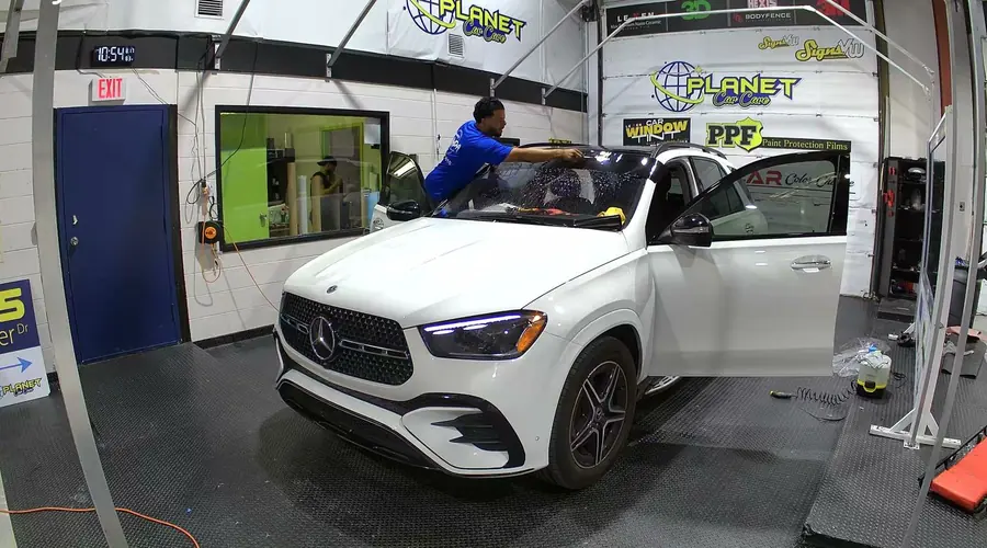 Installer squeegeeing tint film onto glass